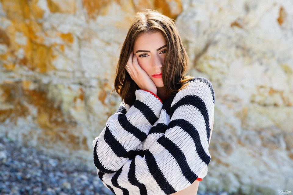 Portrait d’une femme en pull rayé devant un feuillage doré