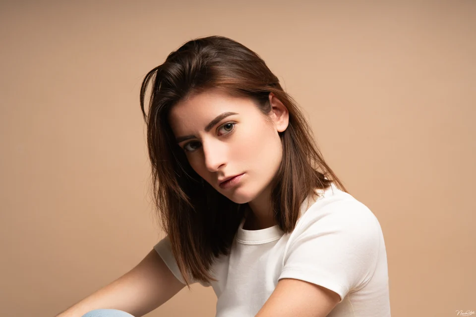 Portrait en studio d’une femme en tee-shirt blanc sur fond beige
