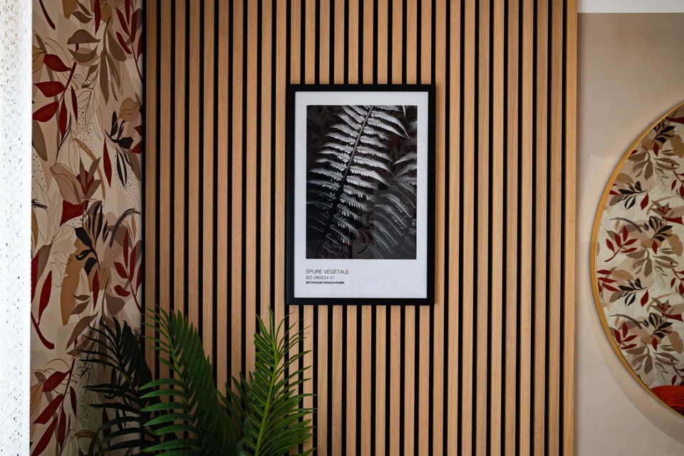 Tableau et feuillages devant un mur à lattes de bois